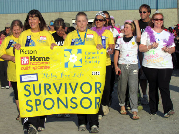 PECI's Nancy Etmanski and Sarah Reddick held the Survivor's Walk banner as more than 150 cancer survivors made their way around the "Victory Lap" at the 2012 Relay for Life event in Picton.