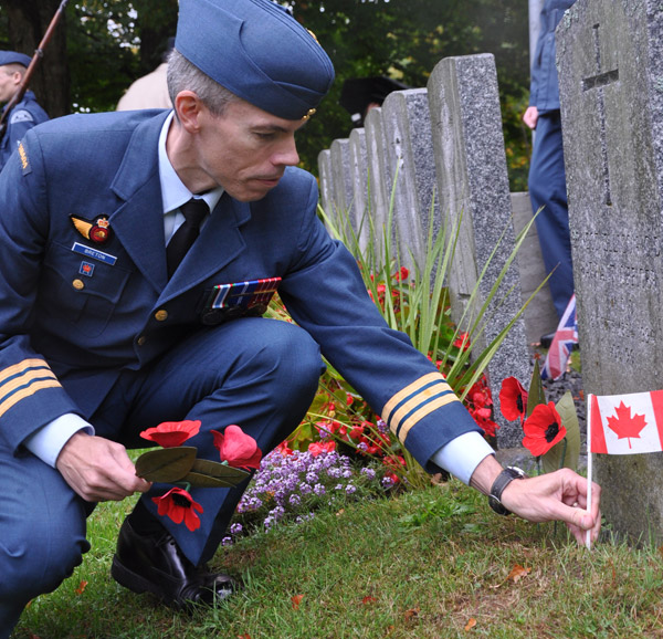 Lt.-Col. Dany Breton, 8 Wing Logistics and Engineering Officer, places a Canadian flag at the base of memorial stone of  one of 200 veterans buried in Glenwood Cemetery in Picton. Photo Ross Lees