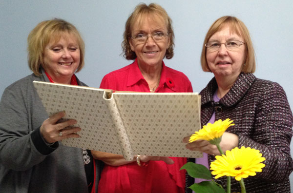 Melanie Payne and Linda Steacy look over photograph albums with Linda Jackson, centre, during her retirement open house.