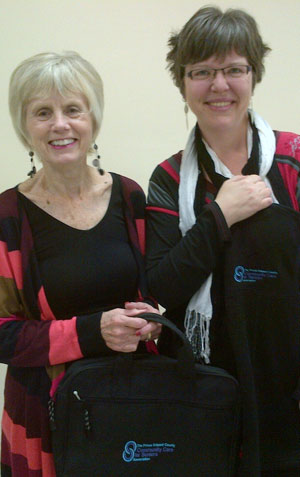 Community Care's President Margaret Werkhoven, left, presents Stephanie MacLaren with a Community Care briefcase and vest on the occasion of her appointment to the Board of Directors.   