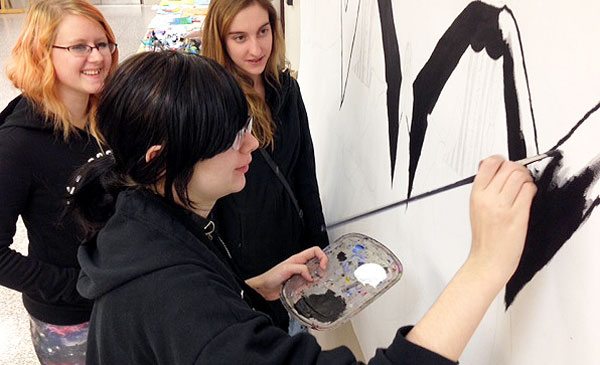 Jessie Reed and Elizabeth Forsyth observe Arionna Scaletta painting.