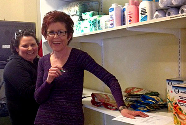 Bev Heuving and and Sabrina Hudson loading the shelves for the new Good Baby Box program at the County's Hub Child and Family Centre.