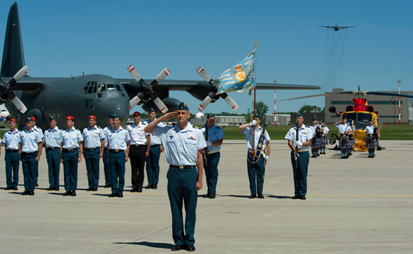 Incoming Lieutenant-Colonel Dany Poitras salutes as a CC130 Hercules approches for a flypast during the 424 Transport and Rescue Squadron Change of Command Parade from outgoing Lieutenant-Colonel (LCol) Jean Bernier on the 8 Wing/CFB Trenton flight line. - Photo by Corporal Owen W. Budge, 8 Wing Imaging  © 2014 DND-MDN Canada