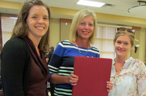Communications officers Emily Tubbs and Ashley Stewart with Grace Nyman, Community Development, holding a copy of the Emergency Plan book.