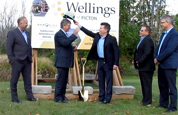 Todd Smith, MPP Prince Edward Hastings watches Mayor Peter Mertens receive his hard hat from Kirk Hoppner, Nautical Lands Group President and CEO while Kevin Pidgeon, COO and Paul Rouleau, CFO, look before the ceremonious digging of the sod to start construction. 