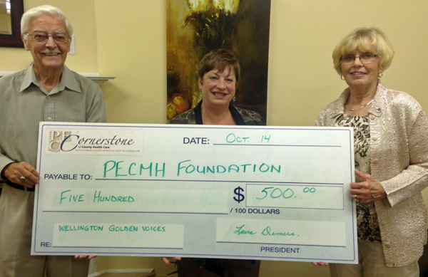 Choir member Mervyn Hicks and director Laura Demers presented Hazel Lloyst, interim director of development with the PECMH Foundation with the funds raised on Tuesday, Oct. 14 at the Wellington on the Lake general meeting.