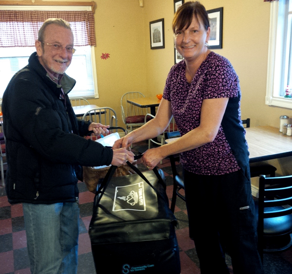 Bruce Hatton, volunteer, and Cyndi Caume, owner of the Mason Jar Restaurant in Carrying Place, prepare to deliver a Meals on Wheels meal to seniors in Ameliasburgh.