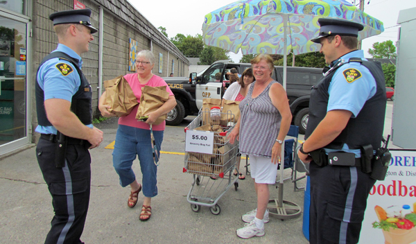 PEC OPP Auxiliary officers Cody Kell, Nick Cassidy and Domenic Maietta assisted customers and Storehouse Food Bank volunteer Lisa Marquardt and director Linda Downey at the Cram the Cruiser event.