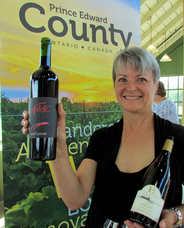 Bev Carnahan, owner and director of the All Canadian Wine Championships, with a bronze winning bottle of 'Flirty' by Waupoos Estates  Winery and a bottle of 2013 Pinot Noir from Huff Estates winery.