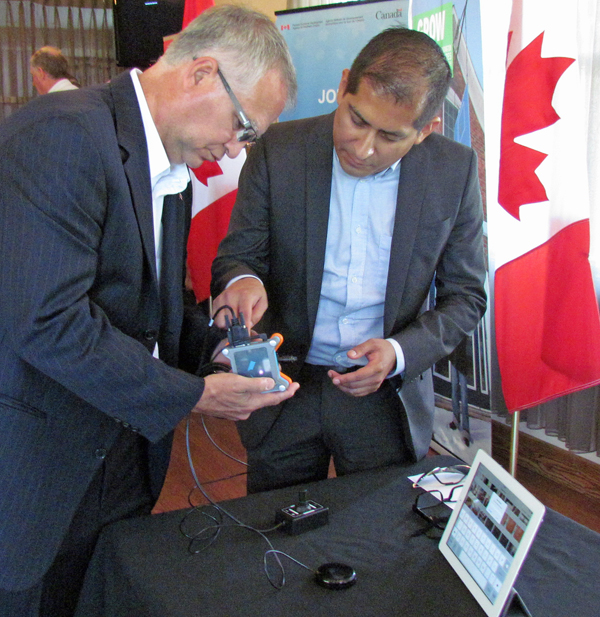 Gary Goodyear, Minister of Sate for FedDev Ontario listens to Mauricio Mezza, CEO of Komodo OpenLab, explain how Tecla makes touch screen devices easier to use for people with disabilities.  