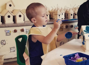 Children’s activities at the open house included trying out riding toys on the new bicycle path in the outdoor garden area; decorating bird houses and fairy houses; and face painting. Here, Remington Leavitt works on a bird house.