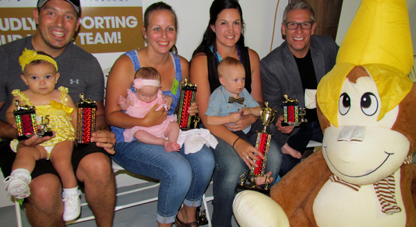 Baby show winners, from left, Greta with dad Justin; Miah, with mom Cassandra and Sebastian, with mom Skye and sponsor Paul Massey with Bananas the monkey, donated for the winner by the midway.
