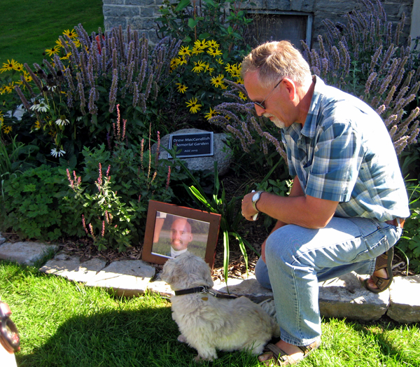 A fieldstone with a plaque inscribed Drew MacCandlish Memorial Garden was revealed by Peter Hovestadt, and Teddy.
