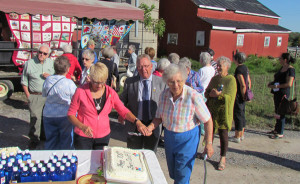 Pat Dubyk, Mayor Robert Quaiff and Irene Hagerman cut the celebration cake. Her anniversary quilt is at back, left. Ginny Klein's is at right.