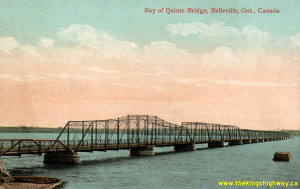 Postcard view of original Belleville Bay Bridge on Hwy 62, formerly Hwy 14 (c1910). It was a toll bridge in 1890, replaced in stages between 1927 and 1931 with new steel truss spans, a swing span, and a short causeway. It was replaced with the current high-level structure in 1982. The Norris Whitney Bridge was dedicated to the memory of the member of the legislative assembly for Prince Edward Lennox Nov. 1951-Sept. 1971 and opened on Dec. 4, 1982, by James Snow, Minister of Transportation and Premier William Davis.