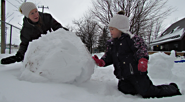 Kalees helps her mom Suzanne roll the snow into place.