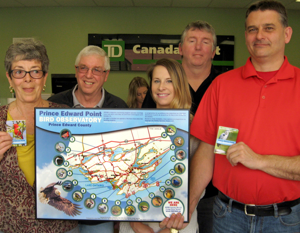 PEPtBO president Cheryl Anderson displays the new Birding Map of the County with photographs by Daniel LaFrance and Gilles Bisson, posing with staff from TD Canada Trust.