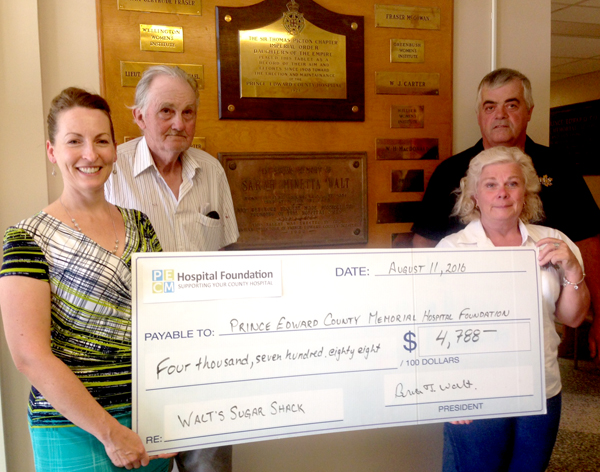 John Walt, Jane Breakall and Brian Walt presented the funds to Penny Rolinski, the Foundation's Executive Director, in front of the plaque honouring Sarah Minette Walt's $2,000 bequest that helped to purchase the first hospital build in George Alcorn's house on Hill Street in 1919.