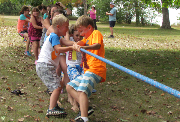 The children work together in a tug of war between them and the adults.