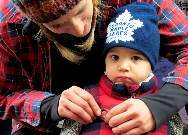 Sonya Szabo pins a button on Beckett Lockwoood, 2, of Toronto, one of the youngest lumberjacks to the festivities. He was in the County on the weekend visiting his uncle Carson Arthur.