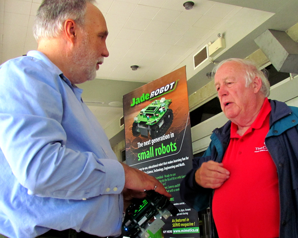 Myke Predko, of Mimetics, demonstrated and explained the small robot for classroom use, to councillor Barry Turpin.