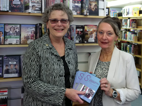 Debbie MacDonald Moynes, Community Care for Seniors executive director, (left) presents DVDs to Barbara Sweet, CEO of the County Library system. 