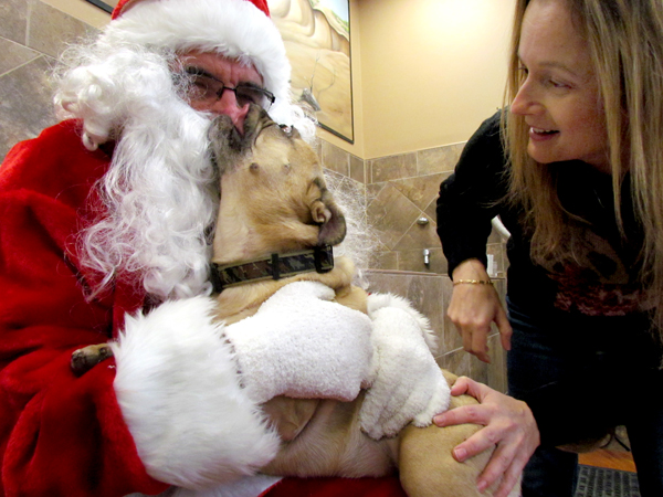 Jet, a French Bulldog pug, gives Santa a kiss while mum Paula Jeffries looks on.